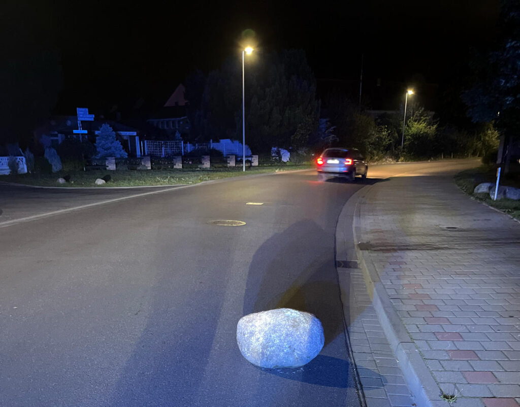 Feldstein auf Fahrbahn gerollt, Stein auf Straße